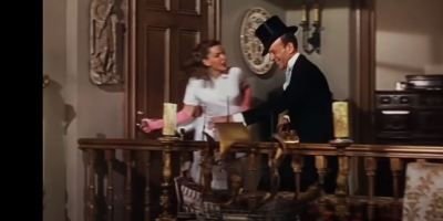 "Easter Parade", film musical (1948), Judy Garland on the left, wearing a white robe, Fred Astaire, with a black cylinder, smiling and looking slightly embarrassed as she defers to him at the door on their way out